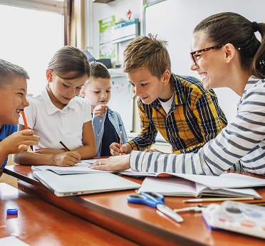 Дети с учителем смотрят тетради